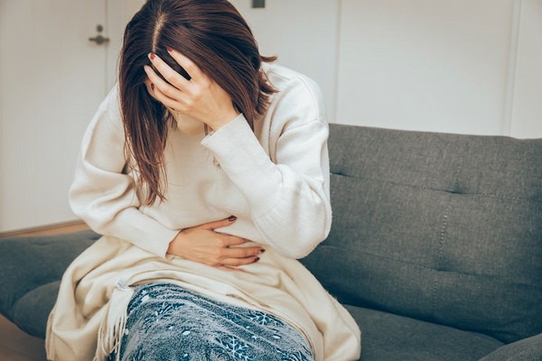 頭とお腹を押さえる女性