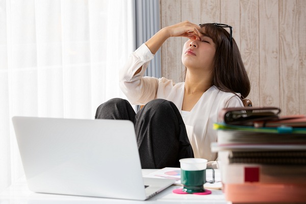 眉間を押さえる女性